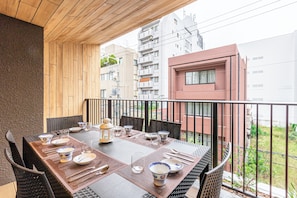 A balcony with a dining table set for four, surrounded by chairs, with a view of residential buildings. - Spacious & Serene 84 ㎡ Retreat near Dotonbori, Kuromon Market & Shinsaibashi (大阪市)