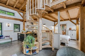 Ein geräumiger Innenraum mit einer Holztreppe, einem Essbereich und einem Bett.