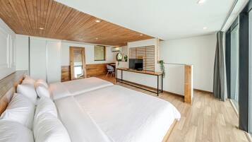 Quarto de hotel moderno com uma cama grande, uma escrivaninha com televisão e uma janela com cortinas.