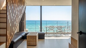 A balcony with a view of the sea, a sofa, a table, and chairs. - Uljin French Paper Pension (Uljin)