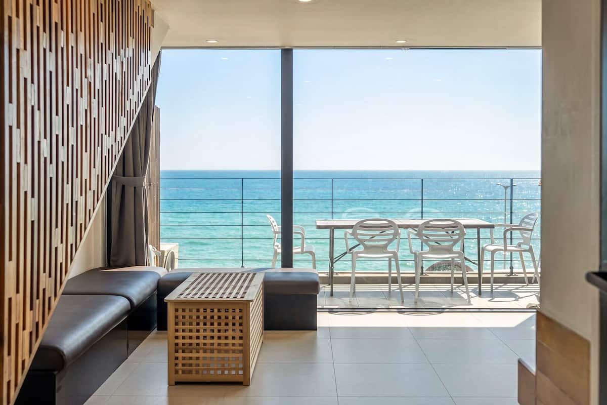 Un balcón con vista al mar, un sofá, una mesa y sillas.