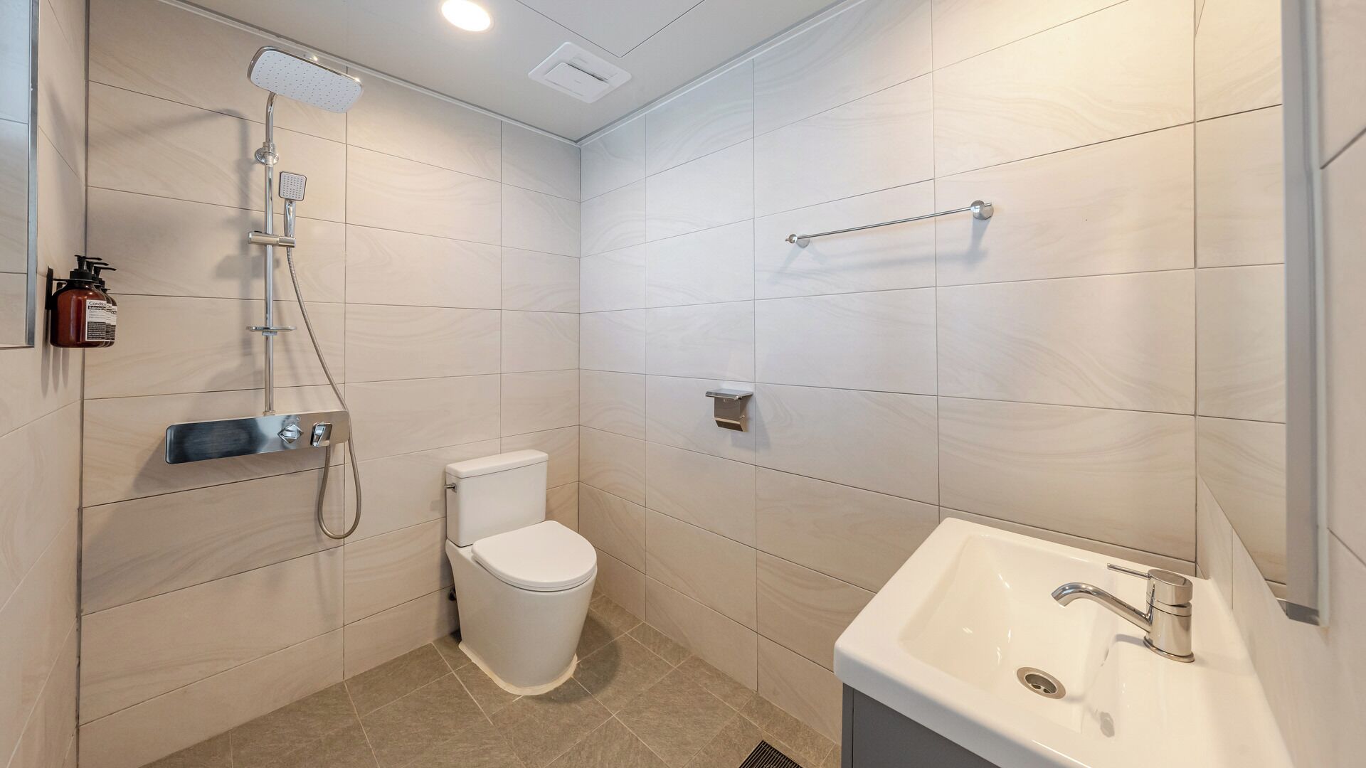 A modern bathroom with a toilet, shower, and sink.