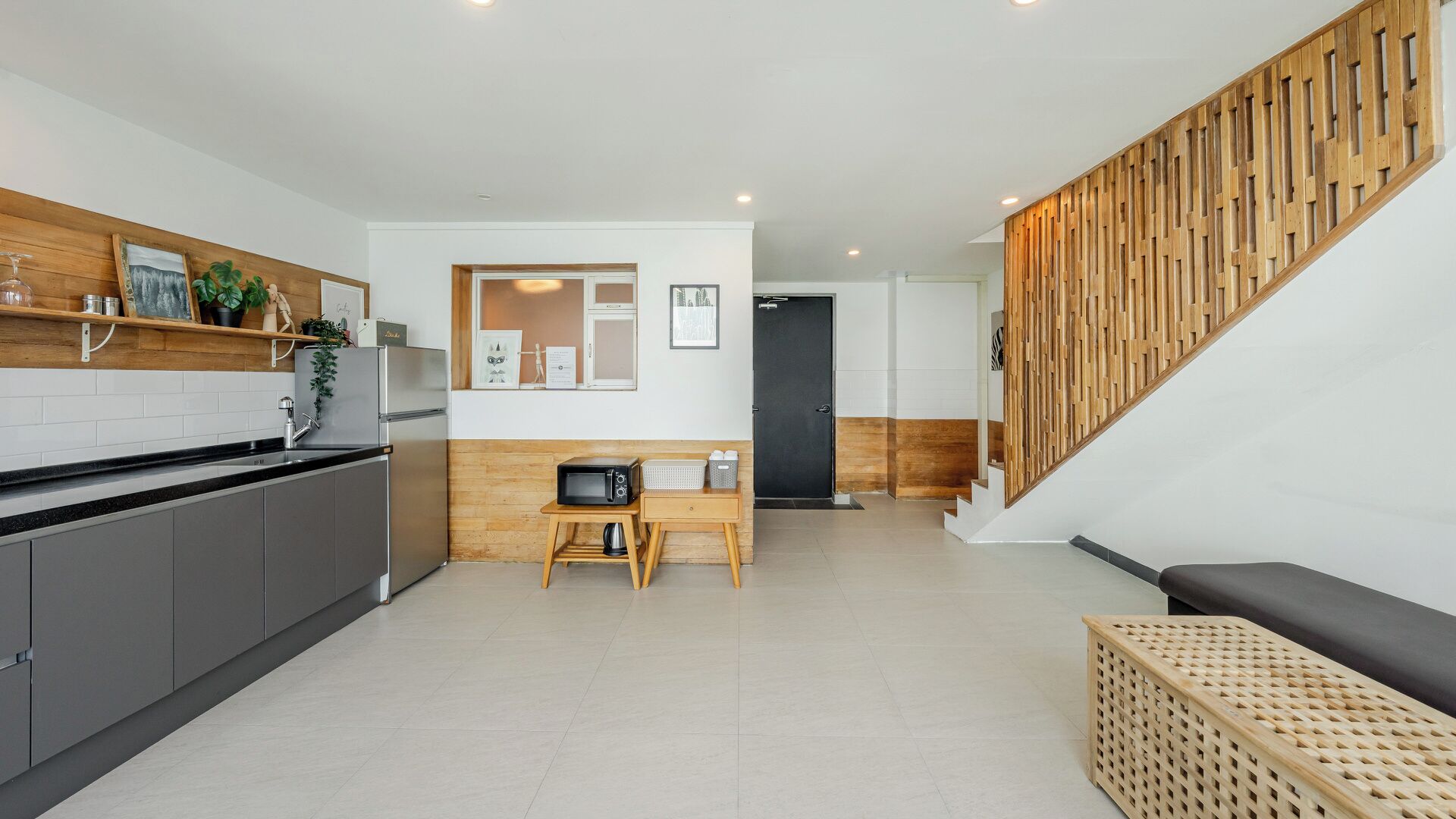 A modern kitchen with grey cabinets, a wooden countertop, and a built-in microwave.