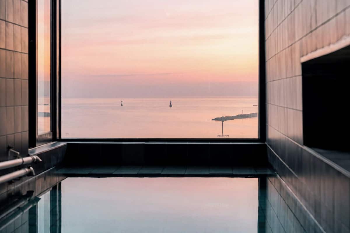 Un interior moderno con un amplio ventanal con vista a un mar tranquilo al atardecer.