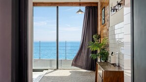 A balcony with a view of the sea, a hanging light fixture, a wooden cabinet, and a potted plant. - Uljin French Paper Pension (Uljin)