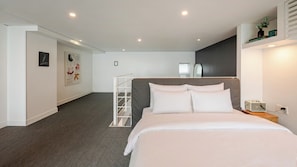 Una habitación de hotel moderna con una cama, una mesita de noche, un espejo y un estante en la pared con libros y un florero.