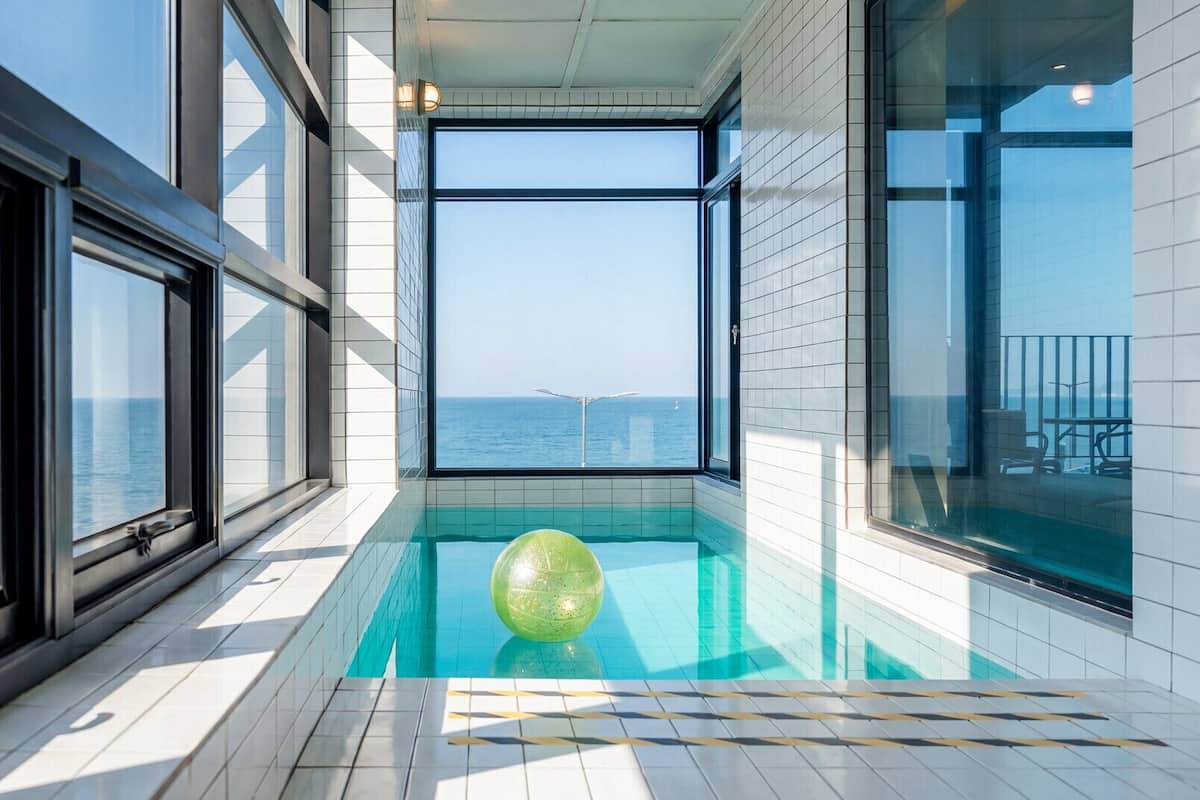 Una piscina interior moderna con vista despejada al mar y una gran esfera verde.