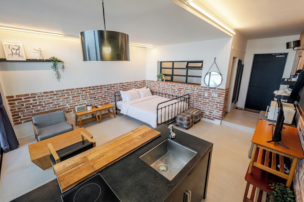 Un espacio habitable moderno con cocina, sofá, mesa de comedor y cama.