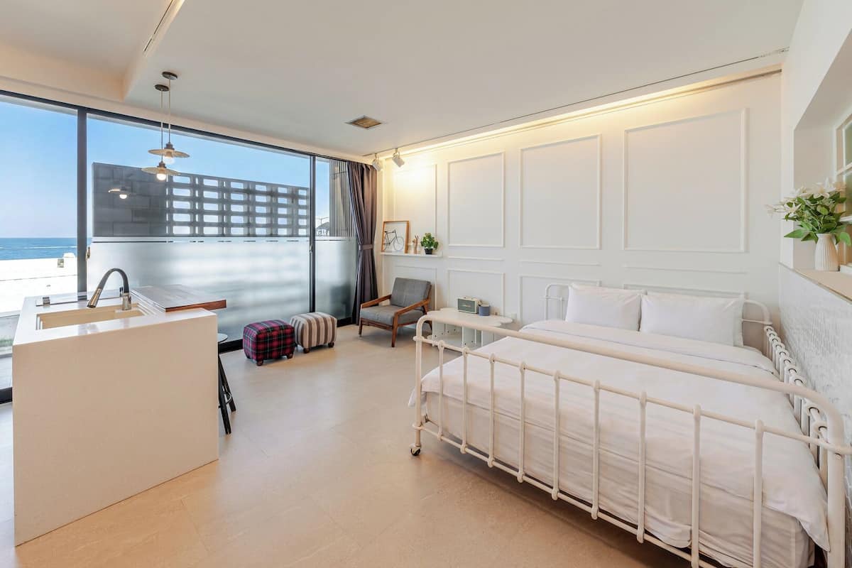 Habitación de hotel moderna con una cama, un escritorio pequeño, una silla y vistas al océano.