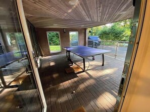 Une pièce avec un plancher en bois, une table de ping-pong et une grande fenêtre.