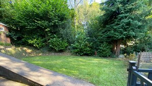 A paved pathway leading to a grassy area with dense greenery and a wooden fence. - Quiet, Modern Ground Floor Annex Near Theatr Clwyd (Mold)