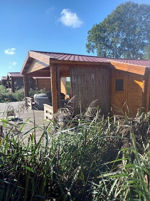 A wooden cabin with a red roof, a covered porch, and a view of the surrounding landscape.