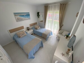 Ein Schlafzimmer mit zwei Betten, einem Schreibtisch, einem Spiegel und einem Bild an der Wand.