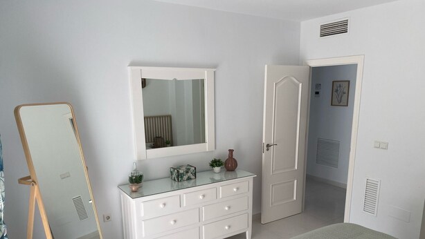 Ein Schlafzimmer mit Bett, Schminktisch, Spiegel und Tür.