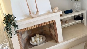 Ein modernes Wohnzimmer mit Kamin, einem flachbildfernseher an der Wand und einem weißen Konsolentisch mit Dekoration.