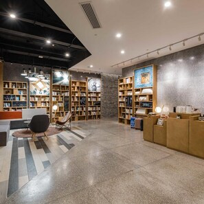 A modern library with multiple bookshelves, a seating area, and a reception desk. - Beijing Temple of Heaven Atour Light Hotel (Beijing)