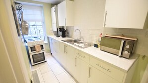 Een keuken met een fornuis, oven, spoelbak en magnetron.