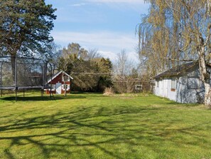 A fenced backyard with a trampoline, a small red building, and a white shed. - 4 Star Holiday Home in Gilleleje (Gilleleje)