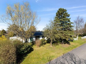A modern house with a sloped roof, surrounded by trees and a fenced yard. - 4 Star Holiday Home in Gilleleje (Gilleleje)