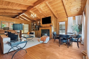 A wooden interior with a fireplace, sofa, coffee table, and bookshelves. - Private Wine Country Escape With Sweeping Valley Views, Hot Tub, Apple Hill (Placerville)