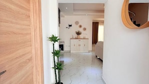 A hallway with a wooden door, a potted plant, a white cabinet, and a round mirror on the wall. - 2-level Villa With Private Pool 3BR (Punta Cana)