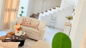 A modern living room with a sofa, coffee table, and staircase leading to an upper floor. - 2-level Villa With Private Pool 3BR (Punta Cana)