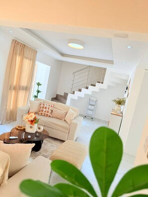 Una sala de estar moderna con sofá, mesa de centro y escalera que conduce a un nivel superior.