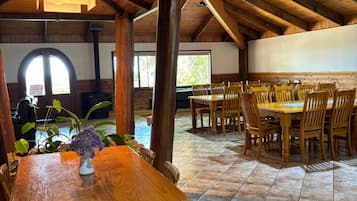 Un comedor amplio con mesas y sillas de madera, una chimenea y vistas al exterior.