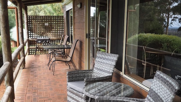 A covered patio with wicker furniture, a brick floor, and large windows. - Augusta Sheoak Chalets (Augusta)