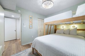A bedroom with a bunk bed, a door, a wall-mounted light fixture, and a framed picture. - Seaside Beach and Racquet 5617 | BeachFront + Pool (Orange Beach)