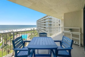 A balcony with a table and chairs, overlooking a beach and a pool. - Seaside Beach and Racquet 5617 | BeachFront + Pool (Orange Beach)