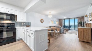 Une cuisine moderne avec des meubles blancs, un grand îlot central et un coin repas offrant une vue agréable.