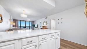 Une cuisine moderne avec des meubles blancs, un grand îlot central et une vue sur l’extérieur.