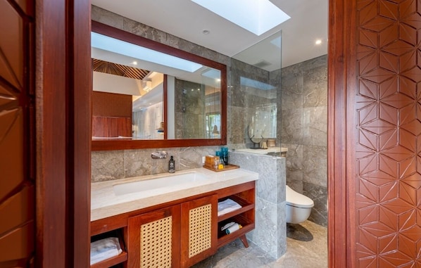 A modern bathroom with a marble vanity, a large mirror, and a shower area.