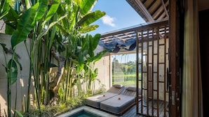 Un espace aménagé au bord de la piscine, avec une terrasse en bois, deux chaises longues et une petite piscine.