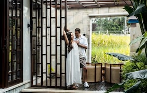 A wooden gate, a person in white, and a person in light-colored clothing standing near a doorway.