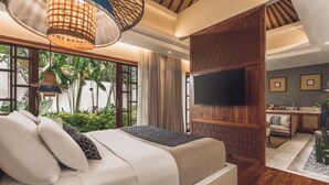 Une chambre avec un lit, un téléviseur fixé sur un panneau en bois, un bureau avec une chaise et une vue sur la verdure à l’extérieur.