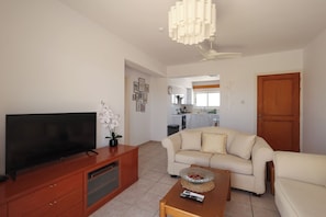 Sala de estar com televisão, sofá, mesa de centro e ventilador de teto.