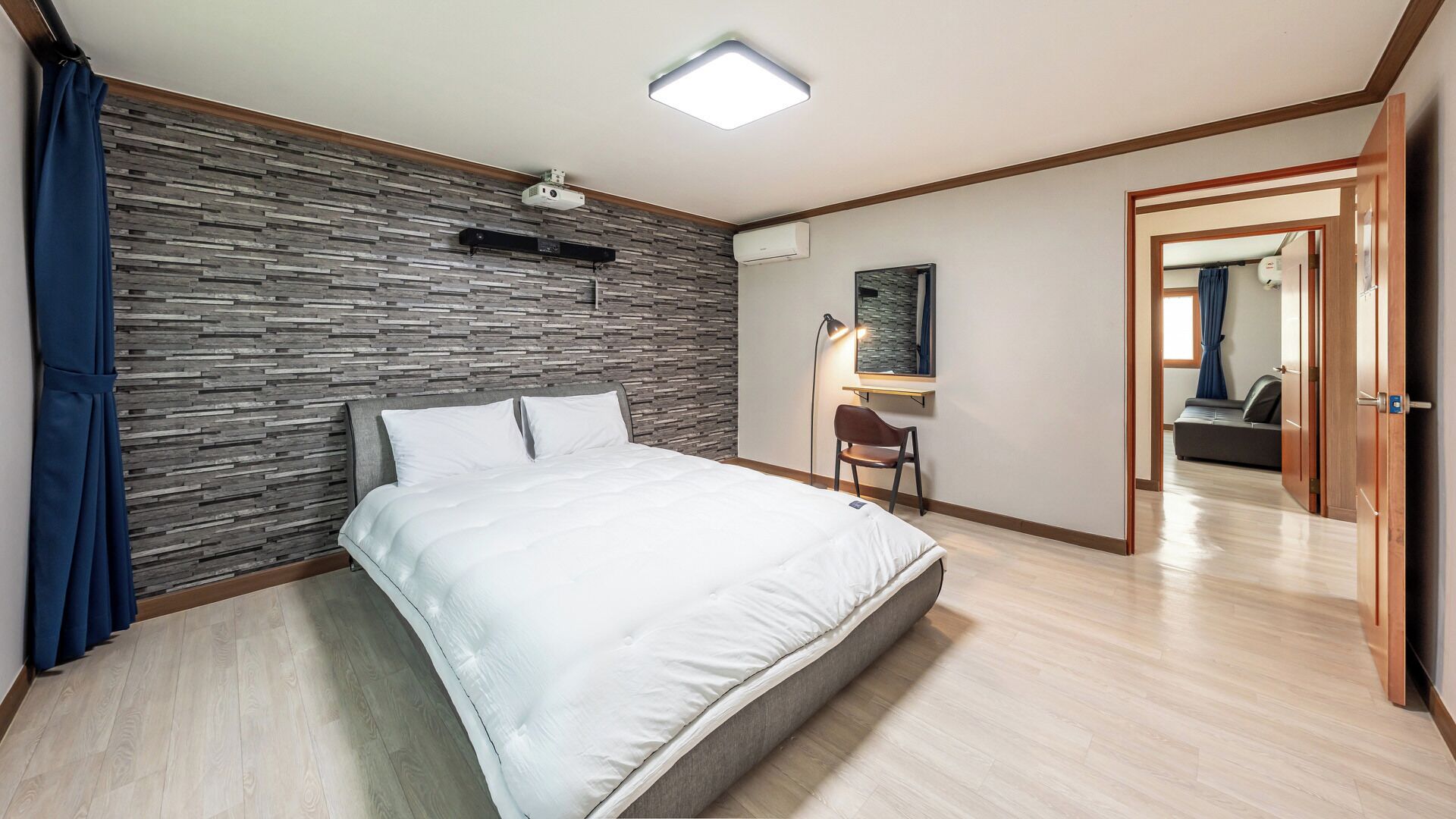 A bedroom with a bed, a desk, a chair, and a wardrobe.