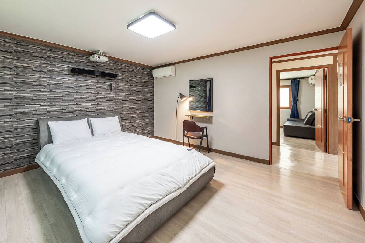 Un dormitorio con una cama, un escritorio, una silla y un armario.