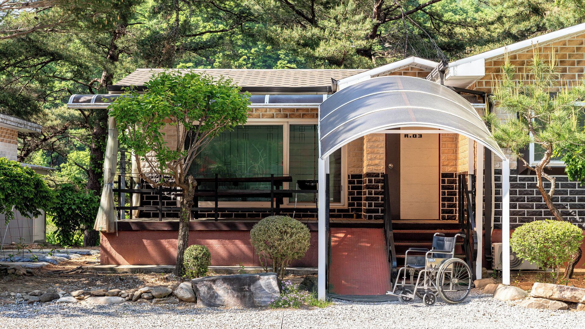 A building with a covered entrance, a wheelchair, and a small garden area.