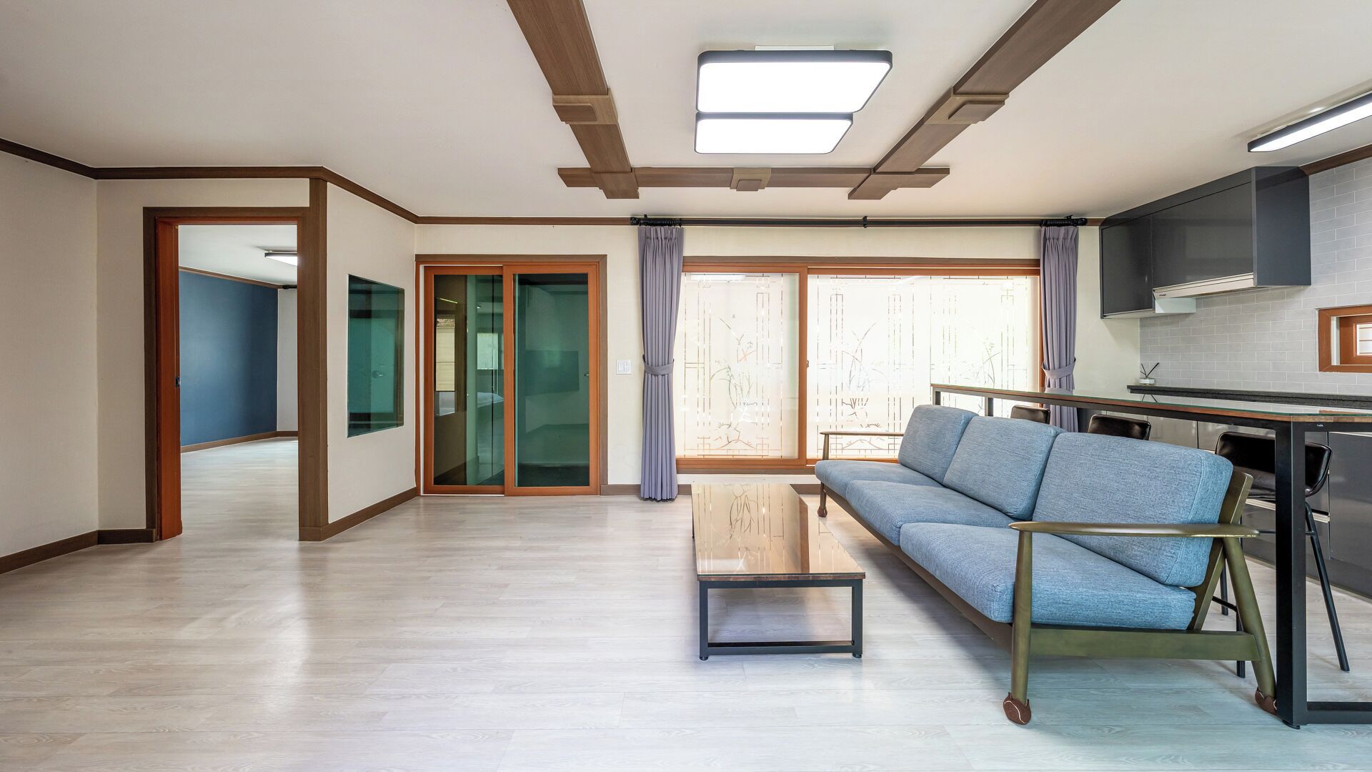 A modern living room with a sofa, a coffee table, and a kitchen area with a TV.