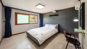 Un dormitorio con cama, escritorio, silla, ventana y lámpara de techo.