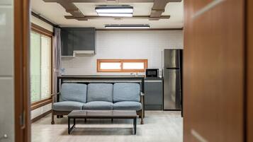 A compact kitchen with a sofa, a microwave, and a refrigerator.