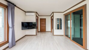 Un pasillo con un televisor de pantalla plana, una puerta y un vidrio que da a una habitación.