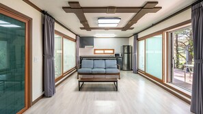 A modern interior with a sofa, kitchen, and large windows. - Yeongwol Waseok U&I Private Pension (Yeongwol-gun)