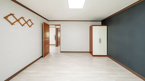 Una habitación con piso de madera, un armario y una puerta que da a otra habitación.