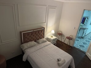 Ein Hotelzimmer mit Bett, Nachttisch, Lampe und zwei Stühlen.