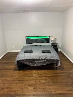 A bedroom with a bed, a nightstand, a lamp, and a ceiling vent. - Modern 3BR Jersey City Retreat Near NYC & FIFA (Jersey City)