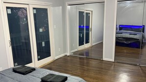 A bedroom with a bed, a sliding glass door, a mirrored closet, and a blue light under the door. - Modern 3BR Jersey City Retreat Near NYC & FIFA (Jersey City)